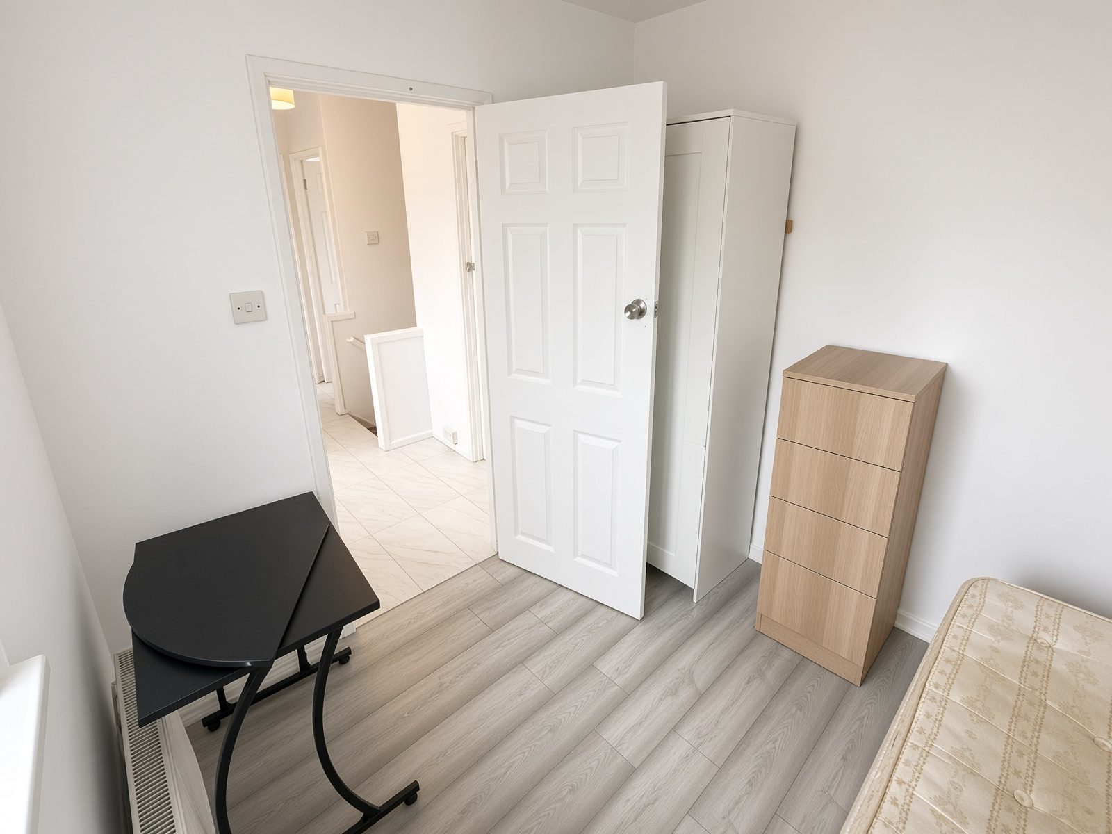Same smaller bedroom looking toward the door, wardrobe, and drawer unit