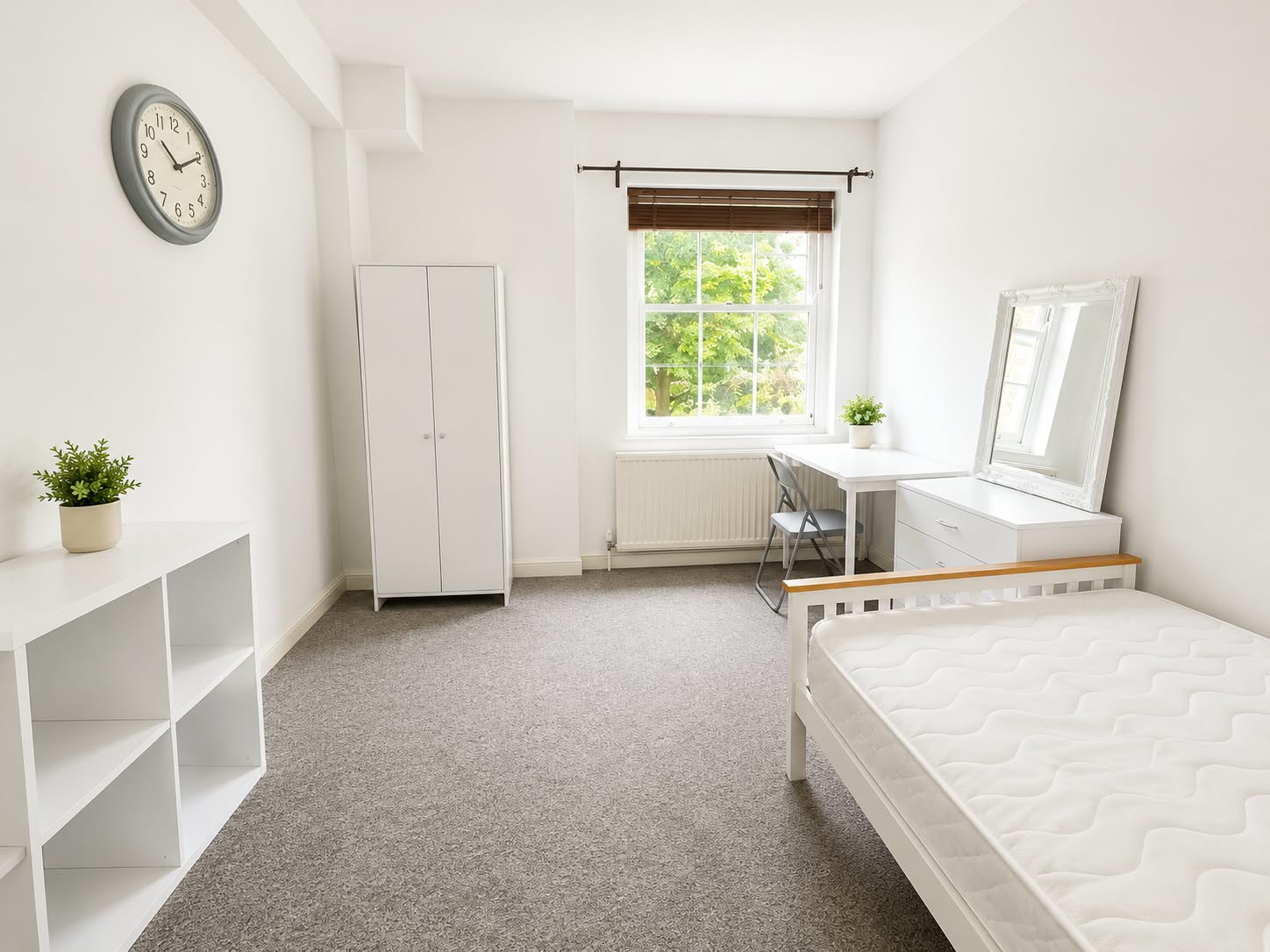 Bedroom 2 with a white bed, desk under the window, and wardrobe